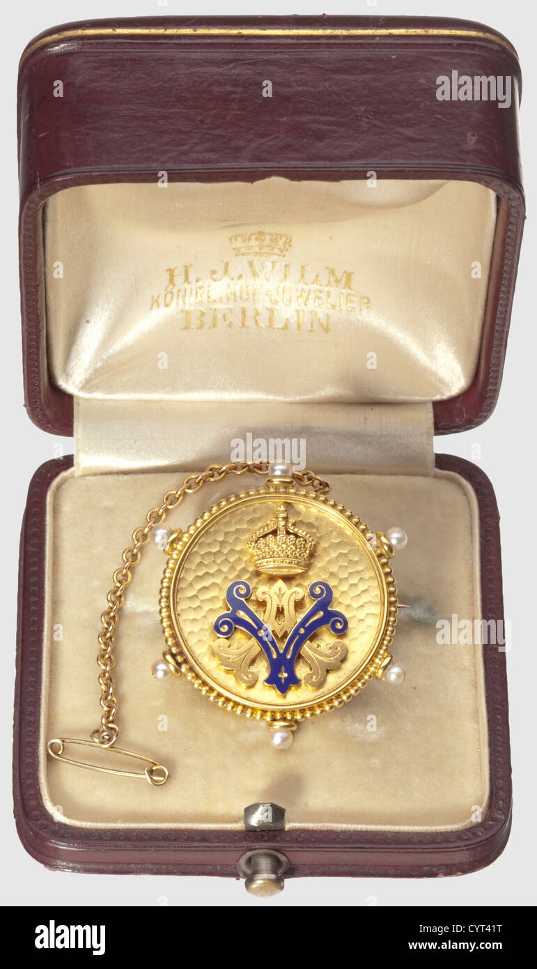 Empress Auguste Victoria,gift brooch in case Circular brooch of gold-plated non-ferrous metal,pin and attached chain of solid gold. The obverse with applied monogram 'AV' surmounted by imperial crown,letter 'V' enamelled in Prussian blue. The edge decorated with six small pearls. In red brown leather case with velvet and silk lining,gold embossed 'AV' surmounted by a crown,maker's stamp 'H. J. Wilm Königl. Hof-Juwelier Berlin',weight ca. 11.5 g,diameter 35 mm,historic,historical,19th century,Prussian,Prussia,German,Germany,militaria,military,ob,Additional-Rights-Clearences-Not Available Stock Photo