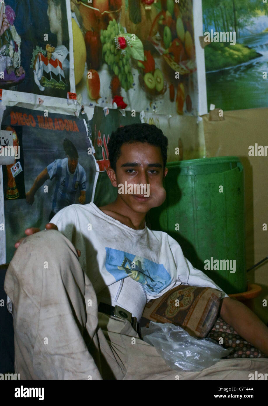 Young Man Lying Down And Chewing Qat In A Room Full Of Posters, Sanaa, Yemen Stock Photo