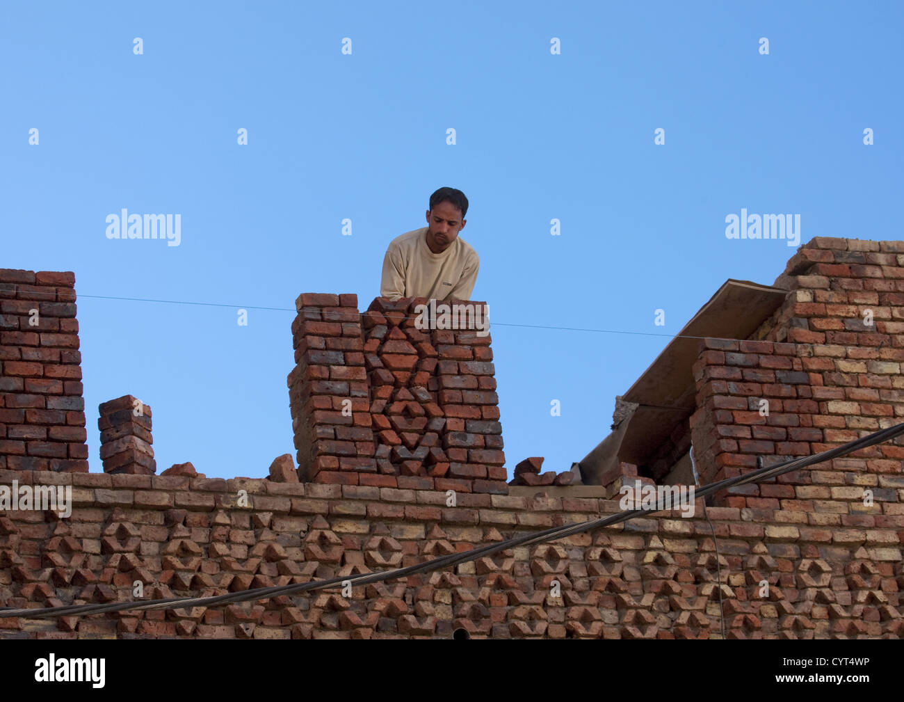 Man Chewing Qat While Adjusting Bricks On A Roof, Sanaa, Yemen Stock Photo