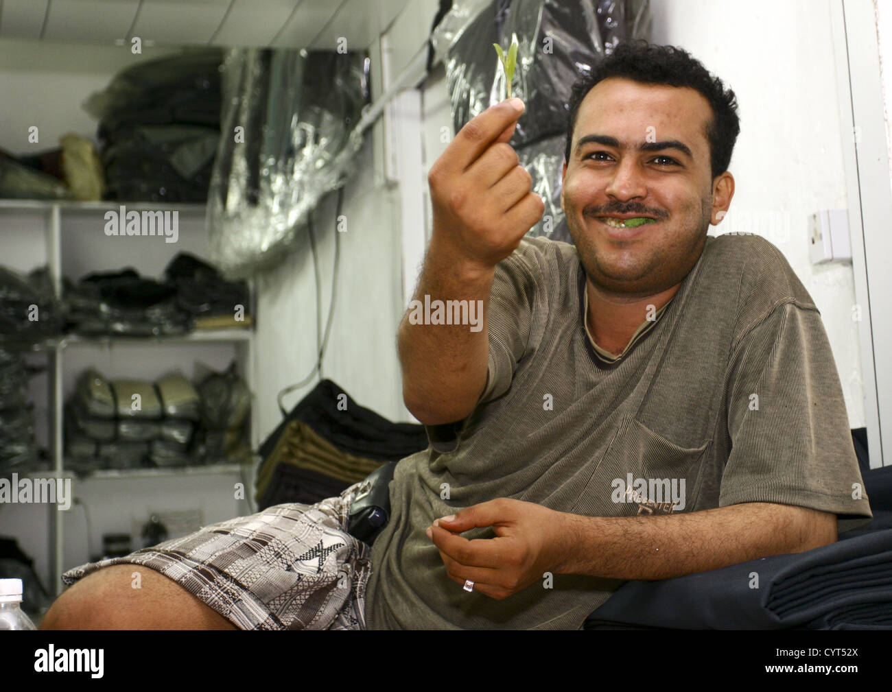 Smiling Man In His Shop Showing A Leaf Of Qat While Chewing, Al Hodeidah Souq, Yemen Stock Photo