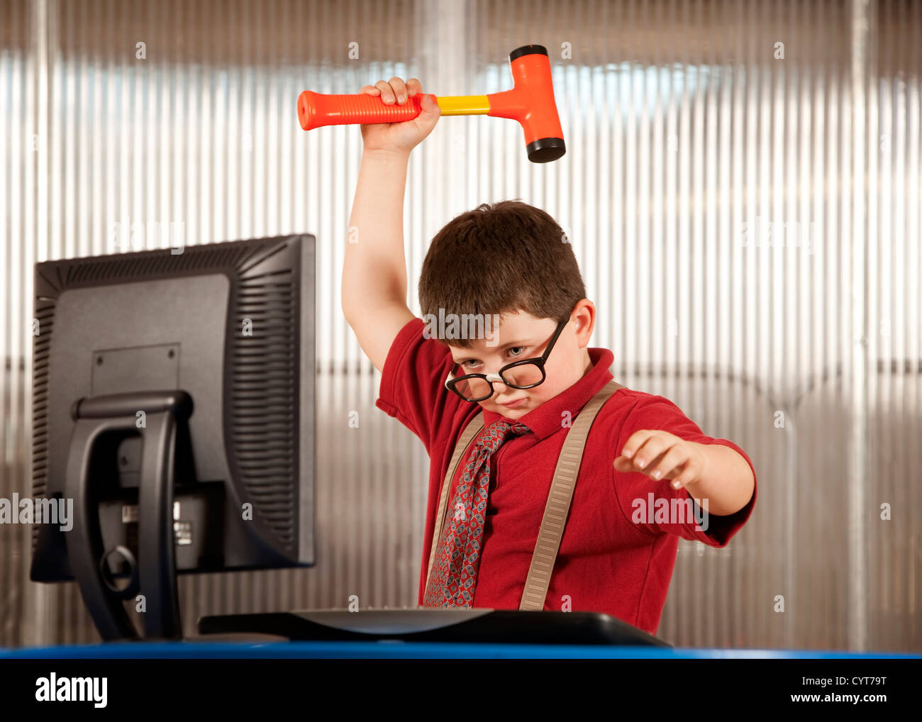 Nerdy young boy smashing his computer with a hammer Stock Photo