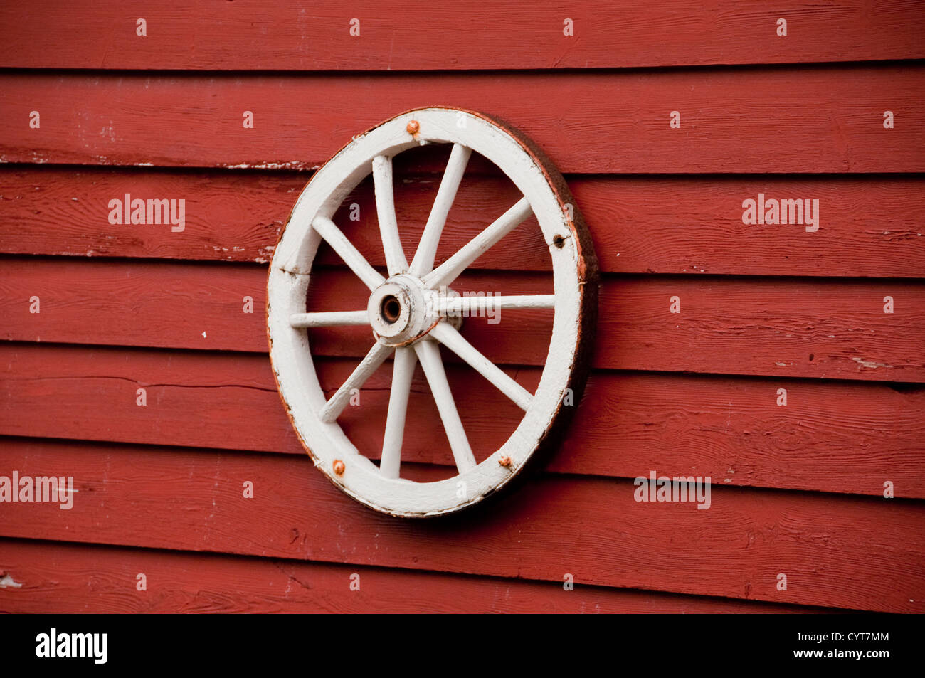A white wagon wheel on a red wall Stock Photo Alamy