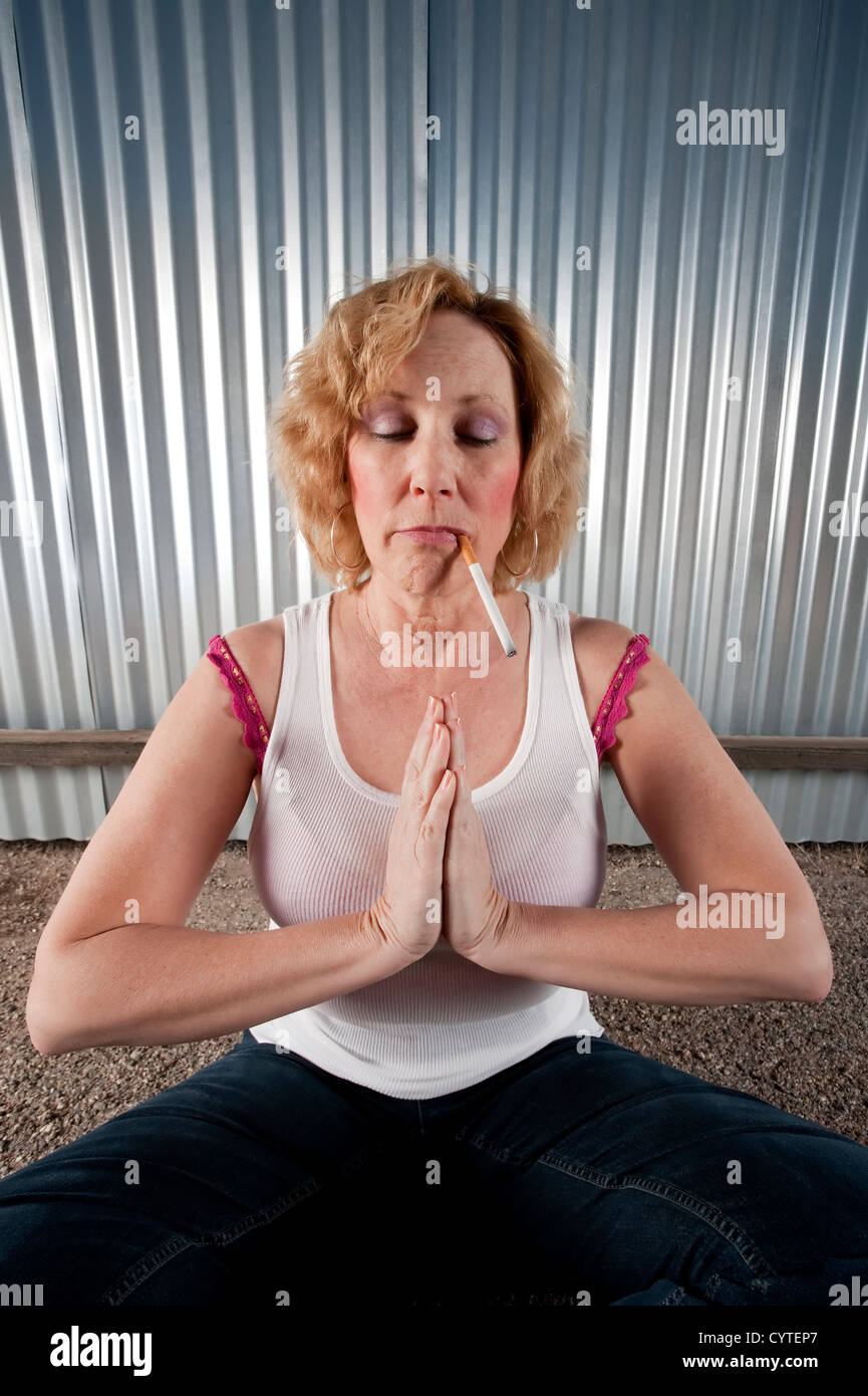 Woman meditating with cigarette in front of corrugated metal Stock Photo