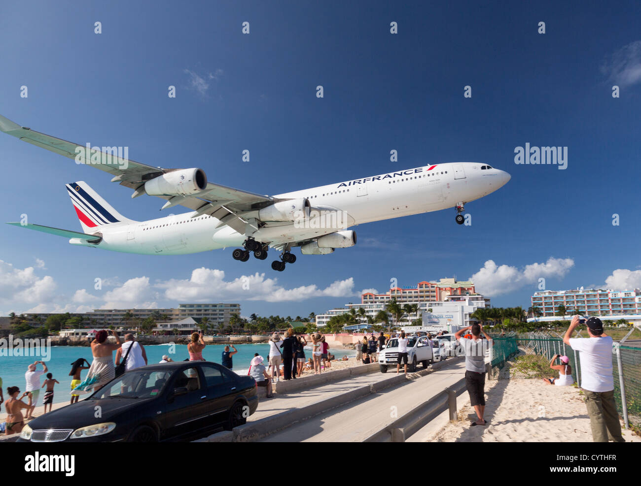 Air France Airbus A340 lands over Maho Beach to Princess Jualiana Airport in St Martin Sint Maarten with tourists watching Stock Photo