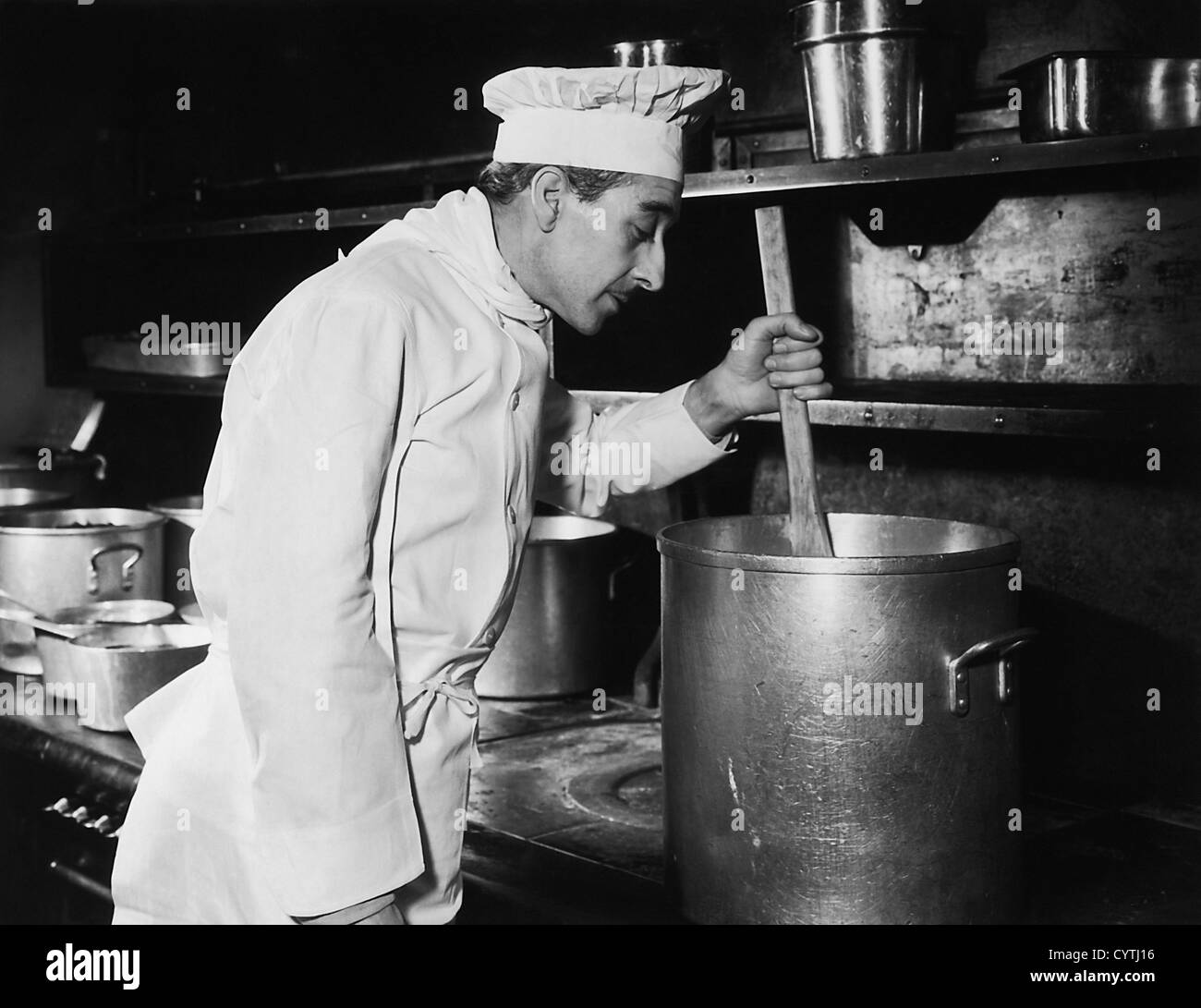 Chef stirring soup in large pot on stove Stock Photo