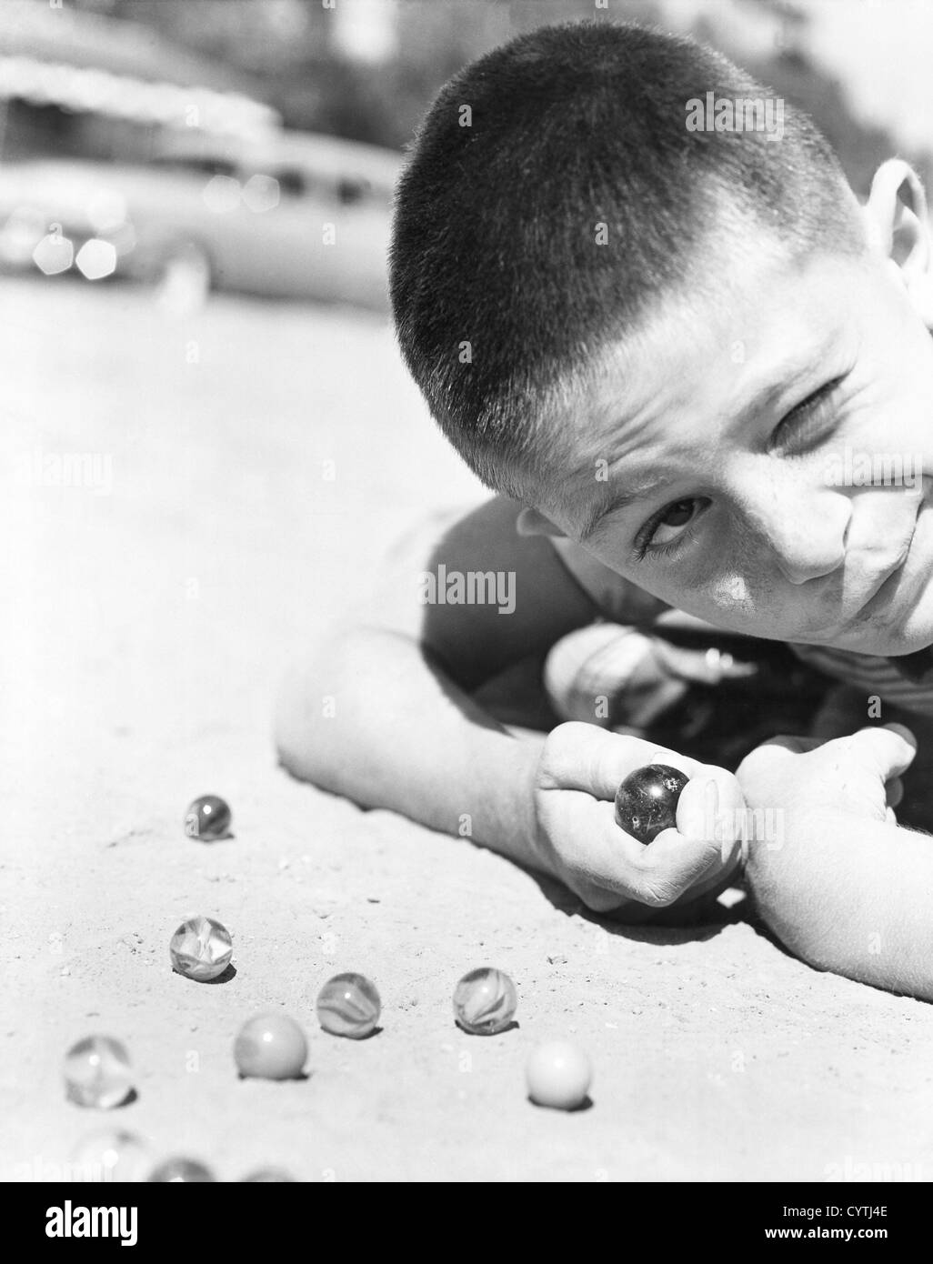 Close-up of young boy playing marbles in the dirt Stock Photo