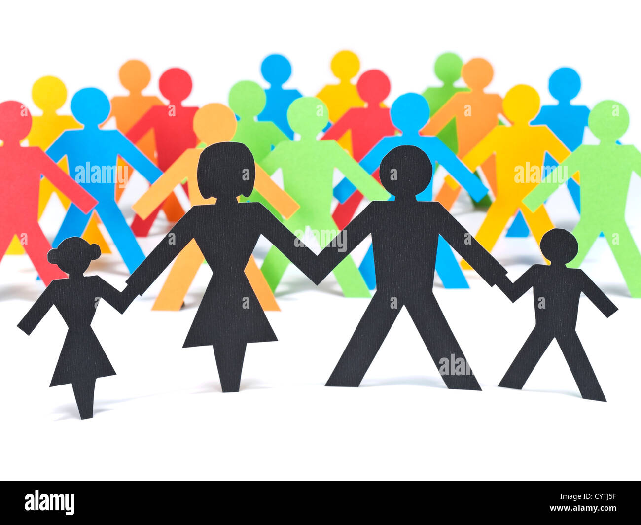 A paper family holding hands in front of a group of multicolor paper men. Stock Photo