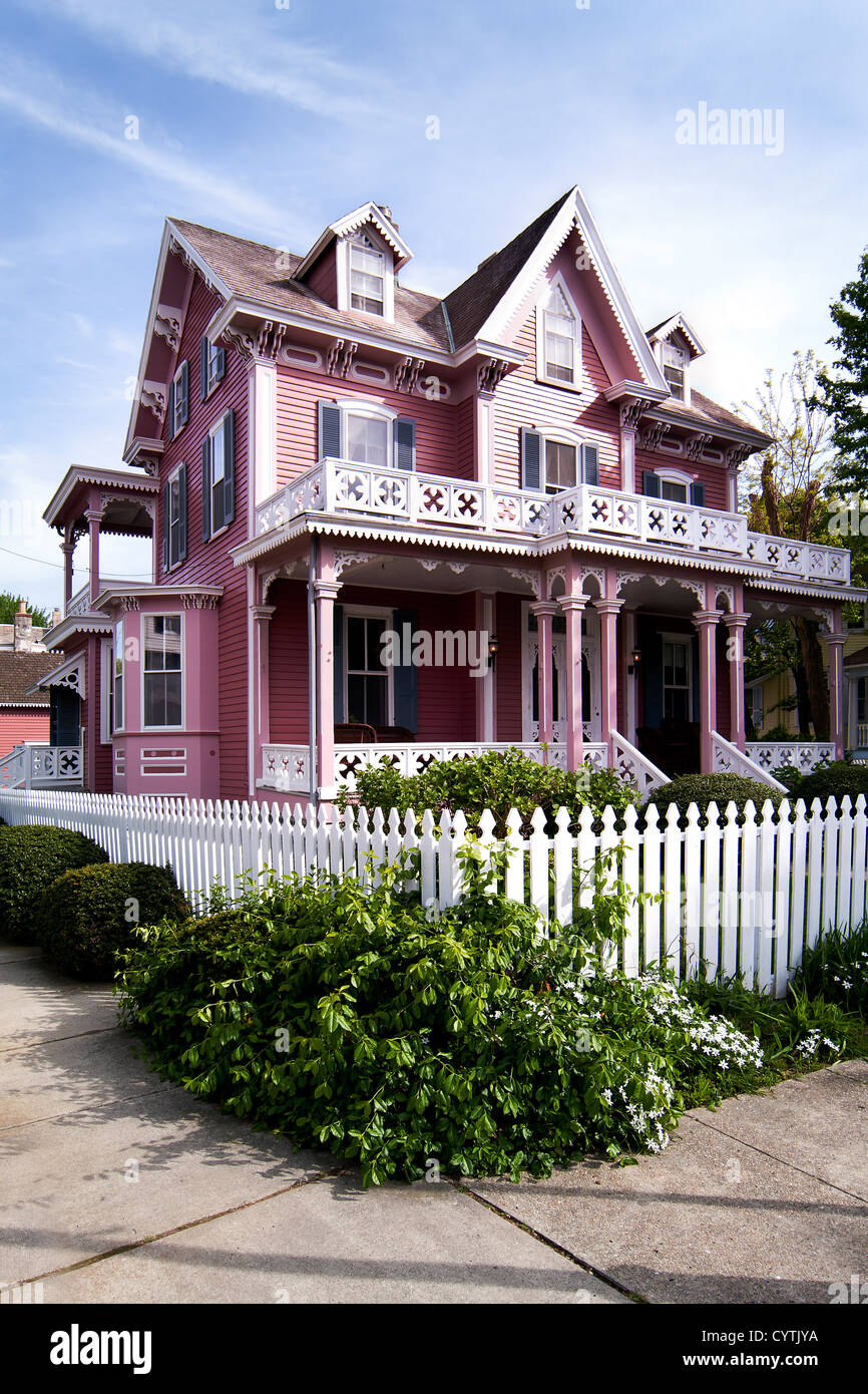Beautiful pink Victorian house with porch and balcony surrounded by a