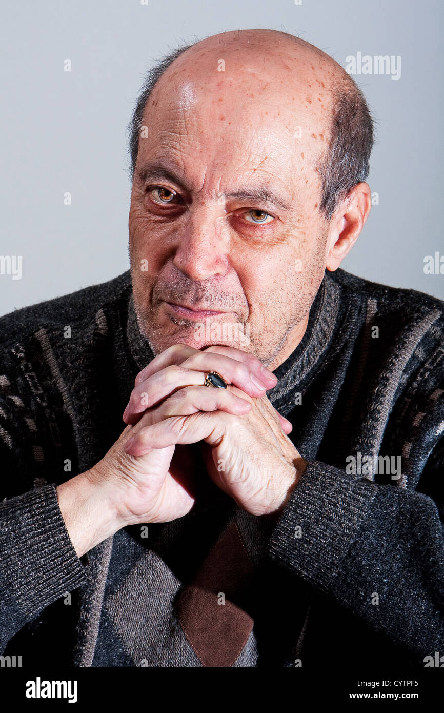 Face of an old man with little hair and bald spot and hands under his