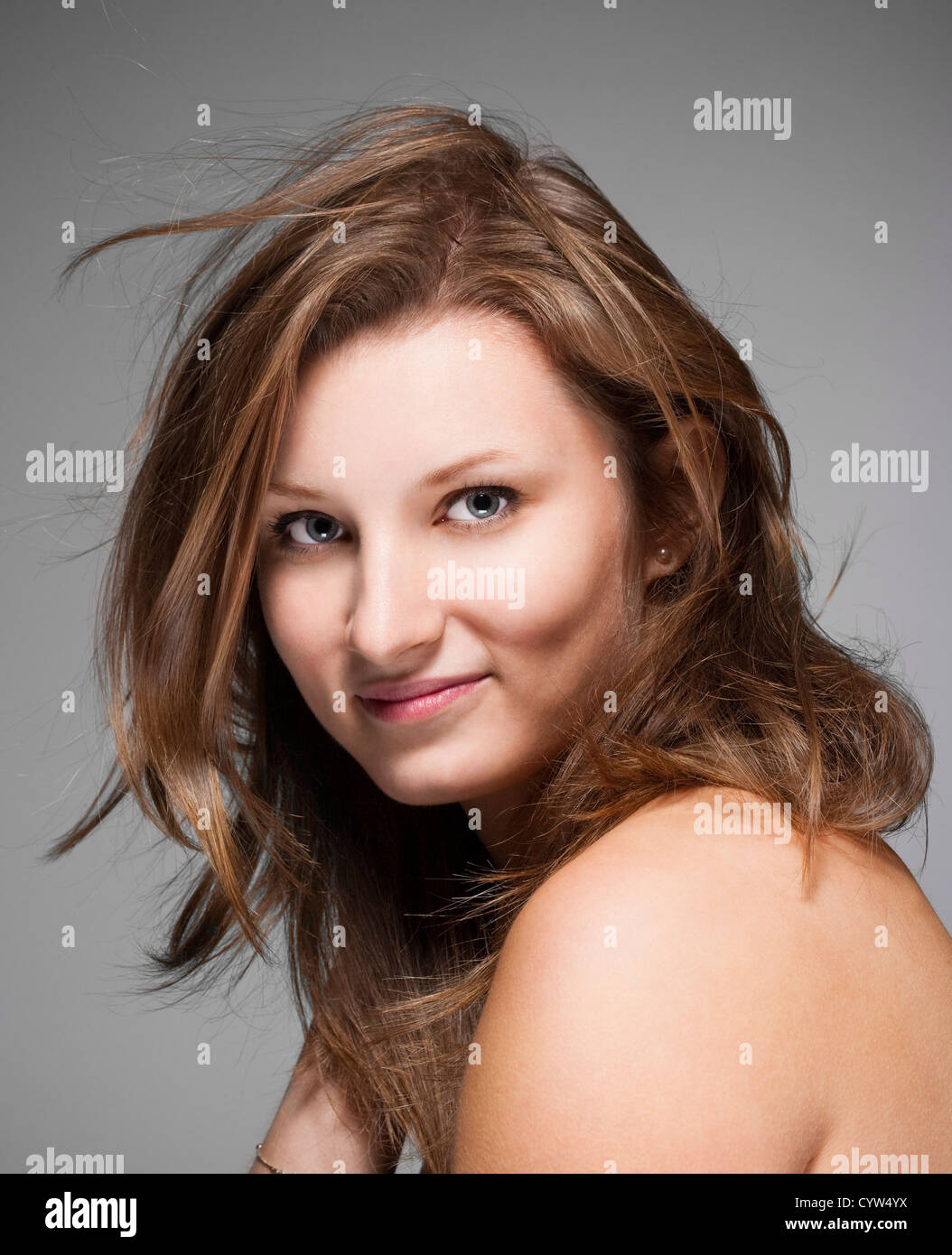 portrait of a young beautiful woman with brown hair against gray ...