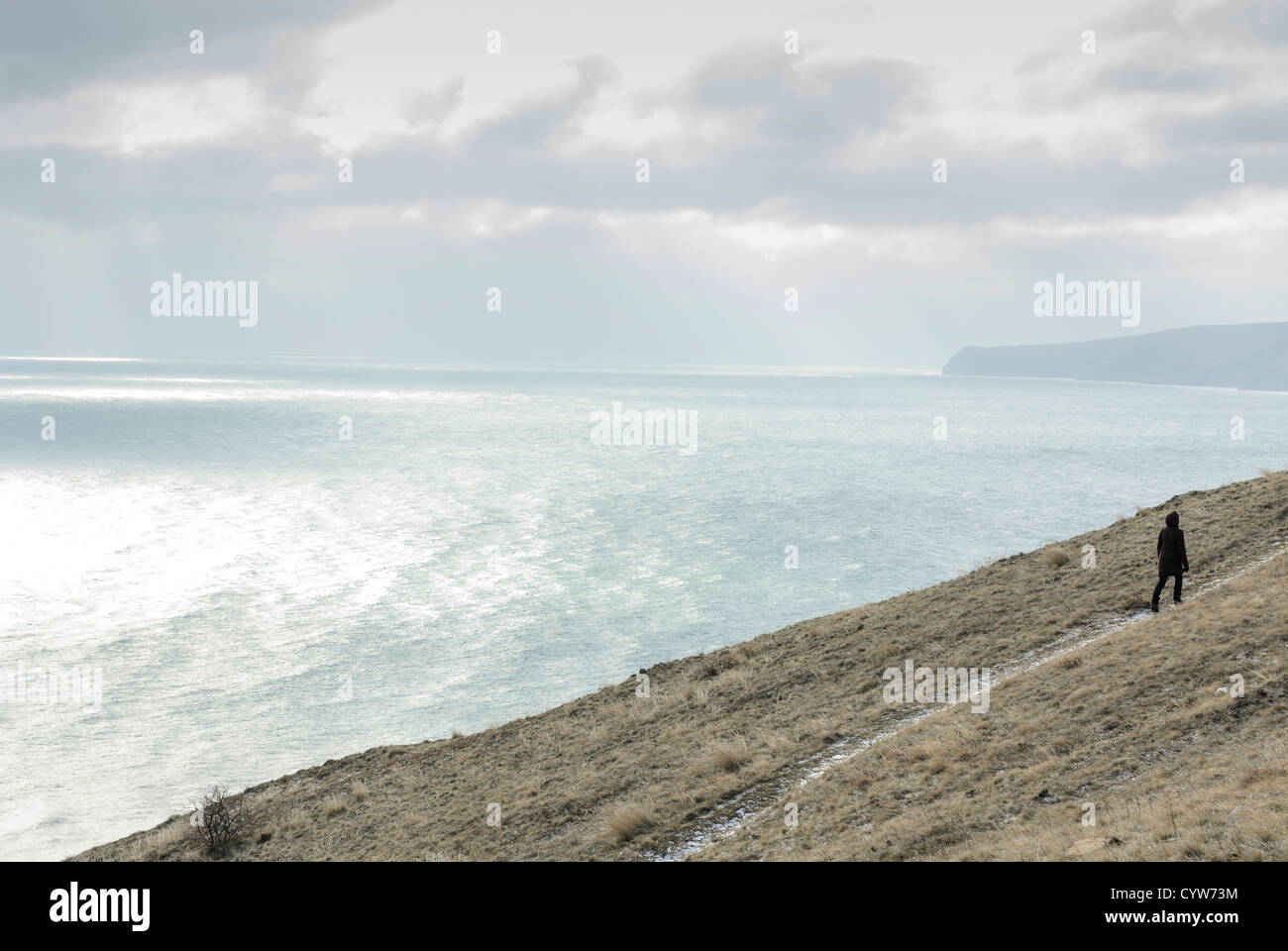 sea view winter person woman cloud cloudscape godrays dramatic walking along lonely Stock Photo