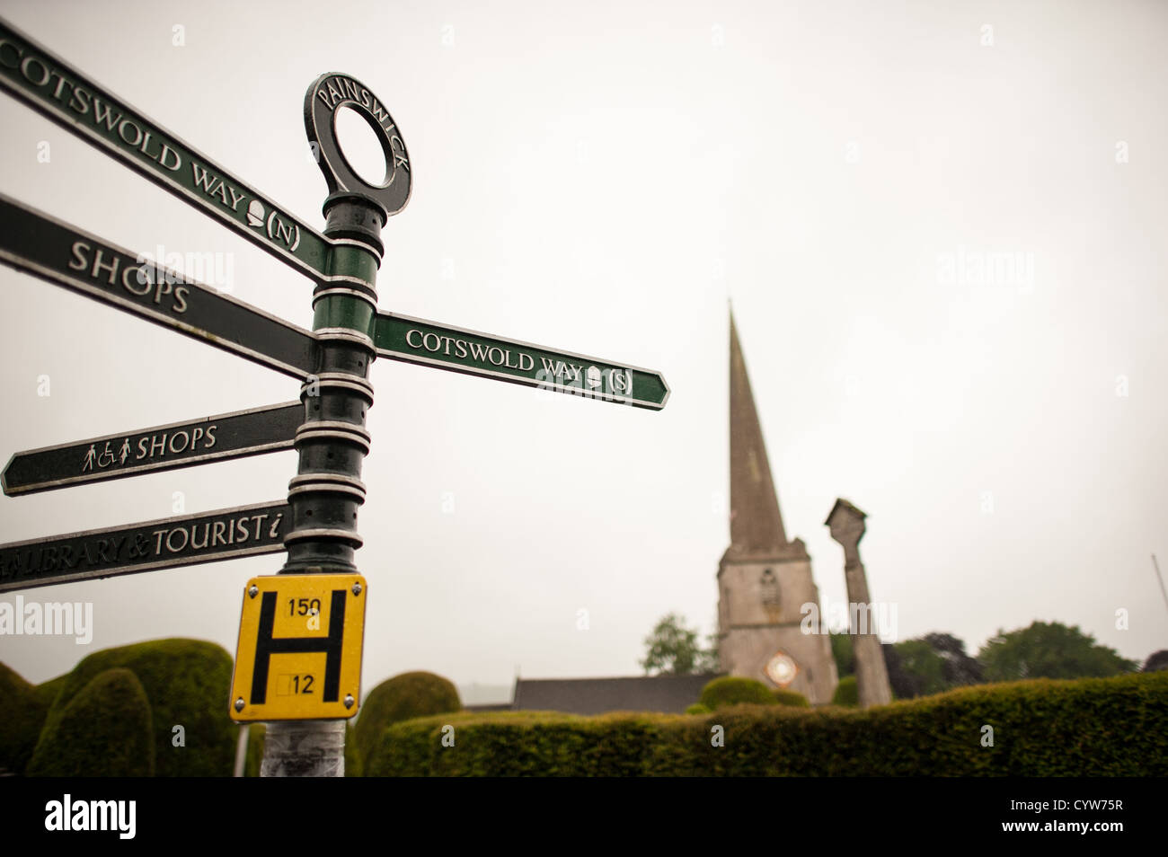 PAINSWICK, United Kingdom — Street signs in the village of Painswick, with the steeple of the Paris Church of St. Mary visible in the background. Stock Photo