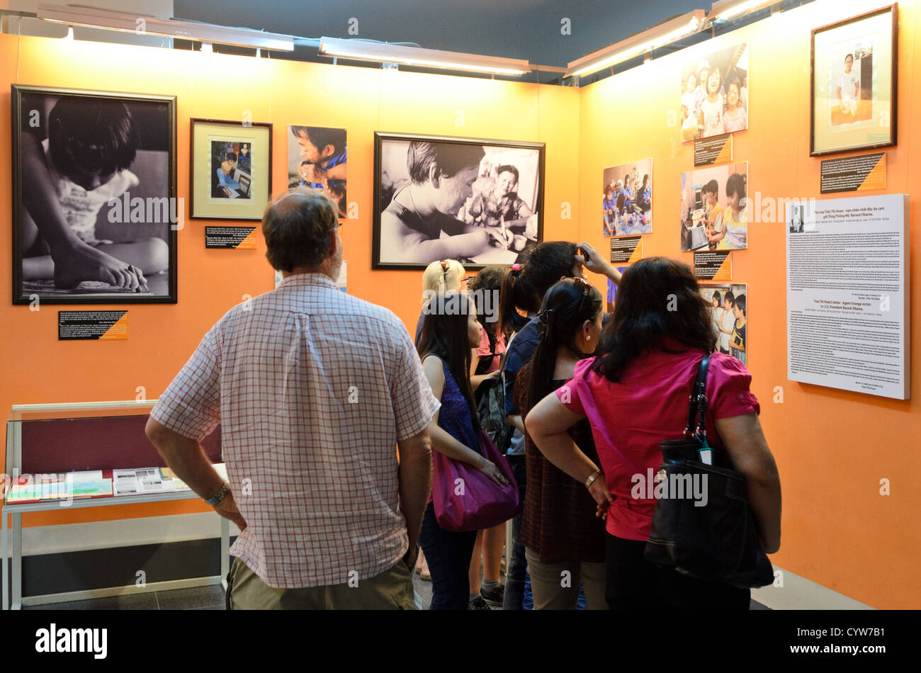 War Remnants Museum Agent Orange Exhibit Ho Chi Minh City // HO CHI MINH CITY, Vietnam — Museum visitors examine photographs documenting the effects of Agent Orange at the War Remnants Museum. The exhibition presents historical documentation of chemical defoliant use during the Vietnam War. The museum maintains these photographs as part of its permanent collection showing the war's long-term impacts. Stock Photo