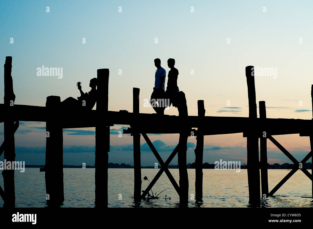People crossing the U Bein bridge by dusk Stock Photo - Alamy