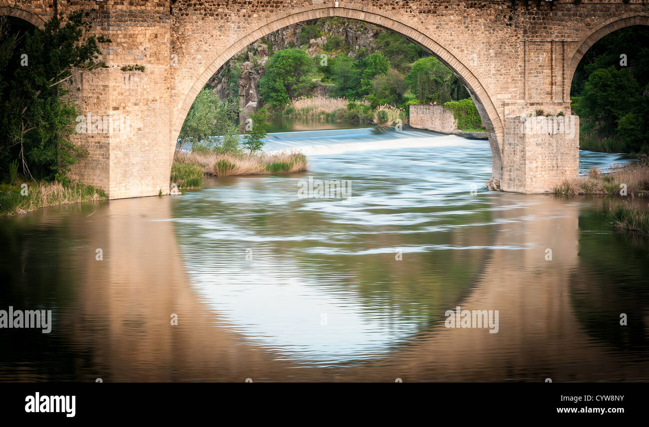 Famous bridge in Toledo, Spain. Arch and reflection in water form big