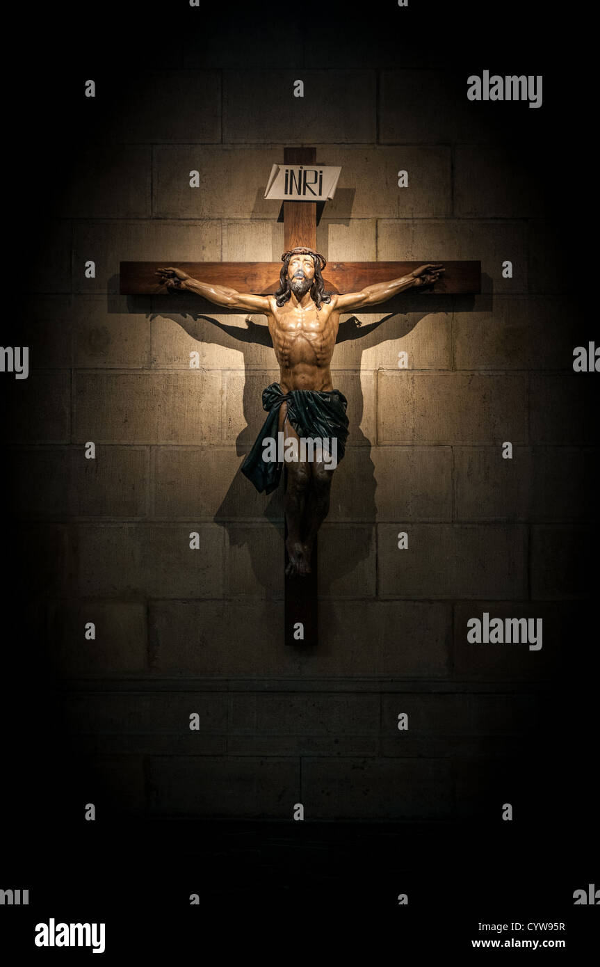 Crucifix on wall in spotlight inside old dark church or cathedral