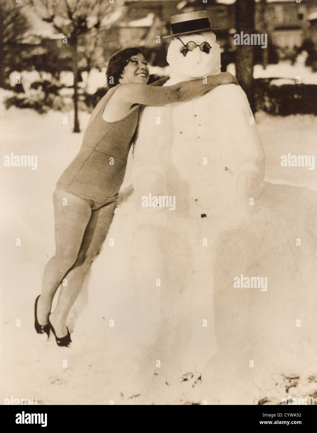 Vintage 1930's press photo of young woman hugging snowman before going in the water for a swim, Manhattan Beach, New York, U.S.A Stock Photo