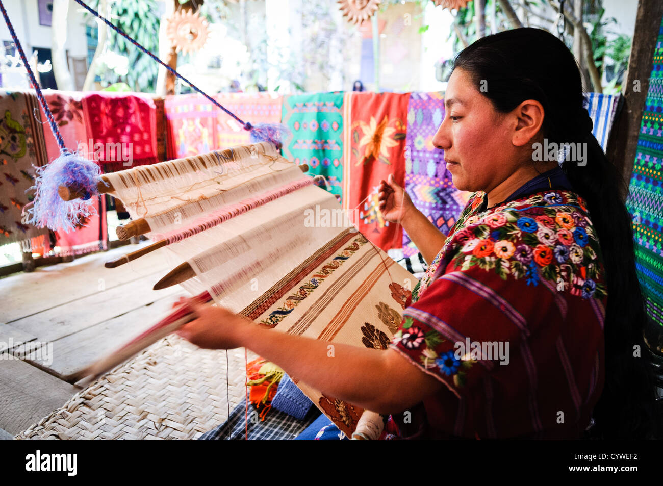 Woman using a traditional loom at Casa del Tejido Antiguo, an indigenous textile museum and market in Antigua, Guatemala Stock Photo