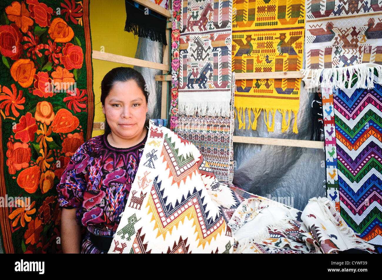 CHICHICASTENANGO, Guatemala - A local woman posing with her woven textiles at the Chichi market. Chichicastenango is an indigenous Maya town in the Guatemalan highlands about 90 miles northwest of Guatemala City and at an elevation of nearly 6,500 feet. It is most famous for its markets on Sundays and Thursdays. Stock Photo