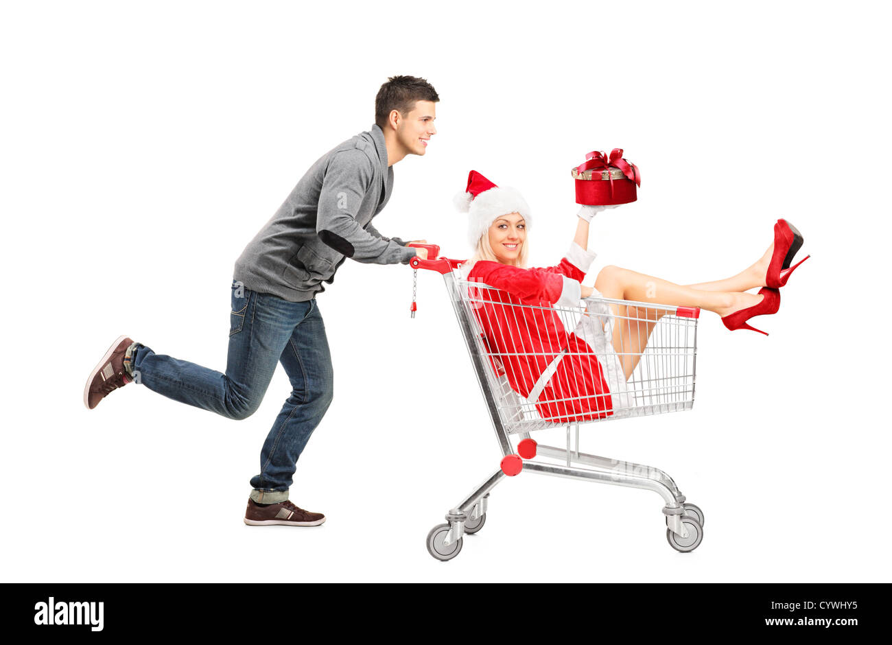 Happy guy pushing a female wearing christmas costume in a shopping cart isolated on white background Stock Photo