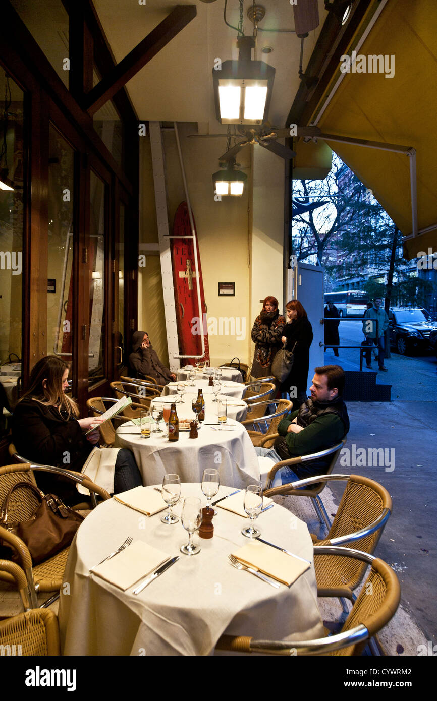 people dressed expensive casual enjoy fine dining outdoors under heat lamps at Cipriani Downtown adjoining chilly sidewalk Stock Photo