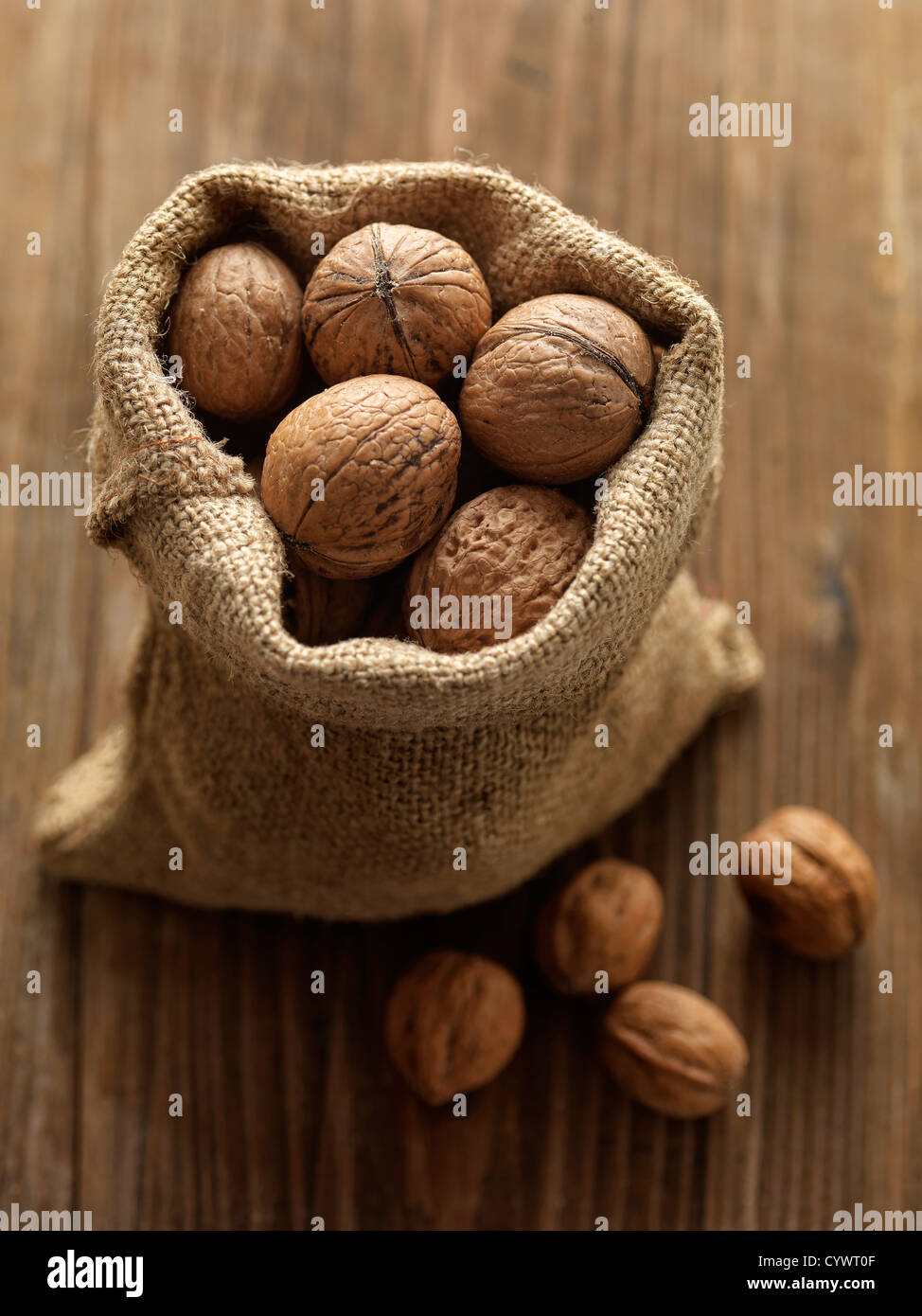 walnuts in woven bag on rustic wooden table Stock Photo