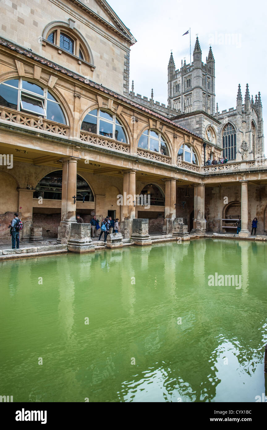 BATH, UK - A view of the waters of the historic Roman Baths in Bath, Somerset, with Bath Cathedral visible in the background. Stock Photo