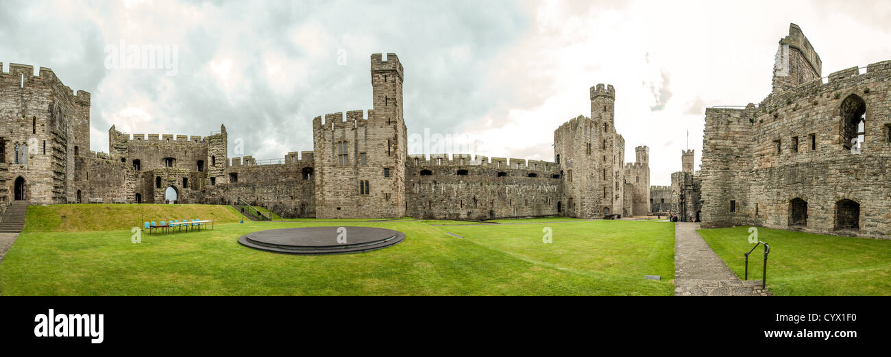 CAERNARFON, Wales - A panorama of the interior of Caernarfon Castle in northwest Wales. The slate dais in the center was used for the investiture ceremony of Prince Charles as Prince of Wales. A castle originally stood on the site dating back to the late 11th century, but in the late 13th century King Edward I commissioned a new structure that stands to this day. It has distinctive towers and is one of the best preserved of the series of castles Edward I commissioned. Stock Photo