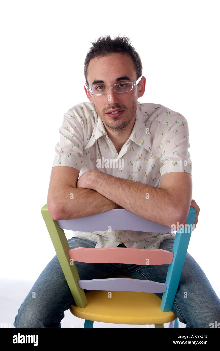 Man sitting on chair backwards leaning arms on back of chair, white