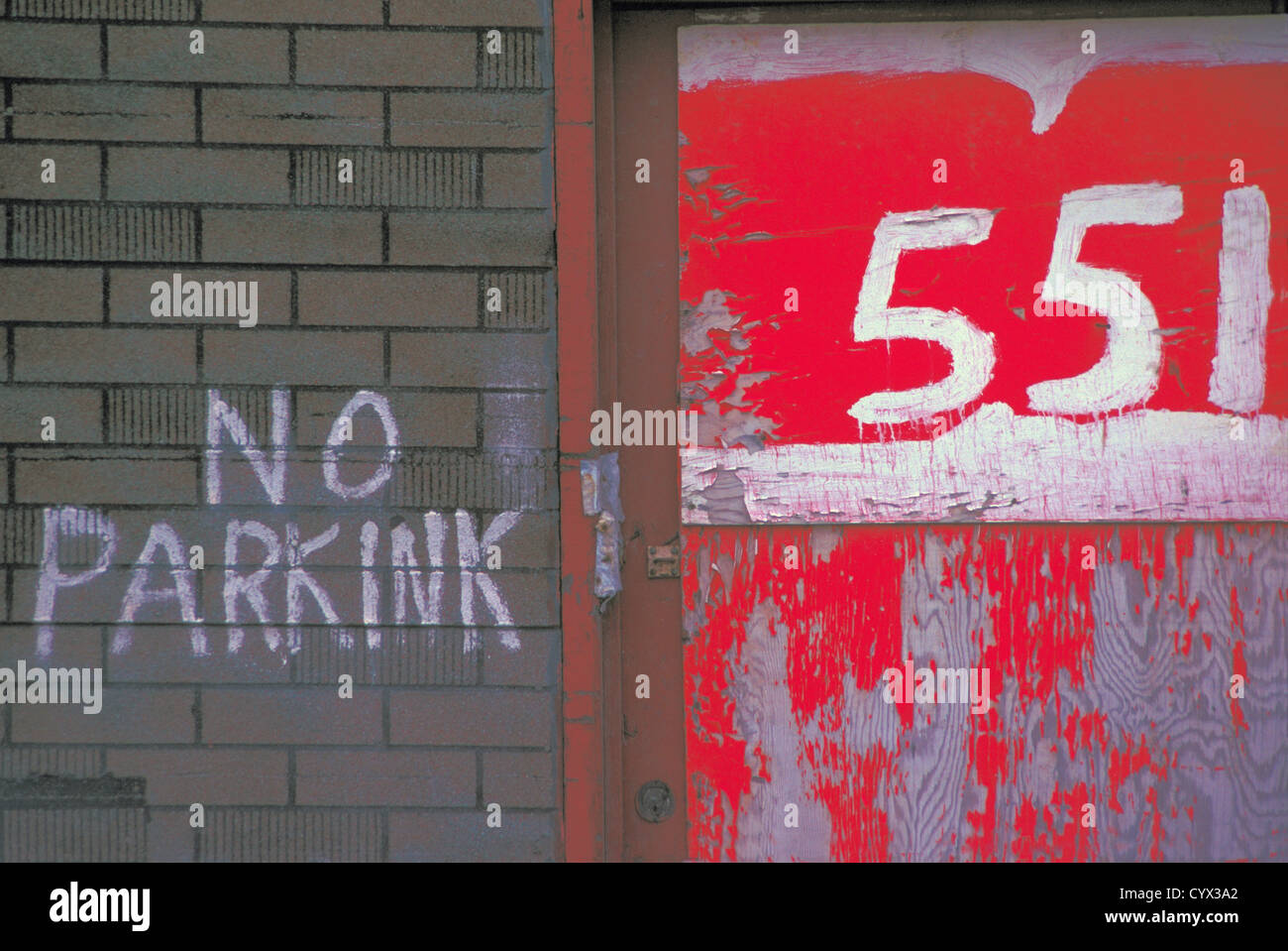 No Parking Sign written on a Brick Wall with Street Address in Red and White Stock Photo