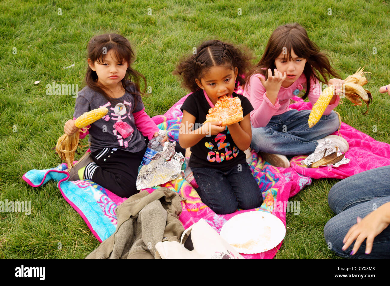 HISPANIC GIRLs CHILDREN EATING PIZZA ON LAWN GREEN GRASS FOOD EAT