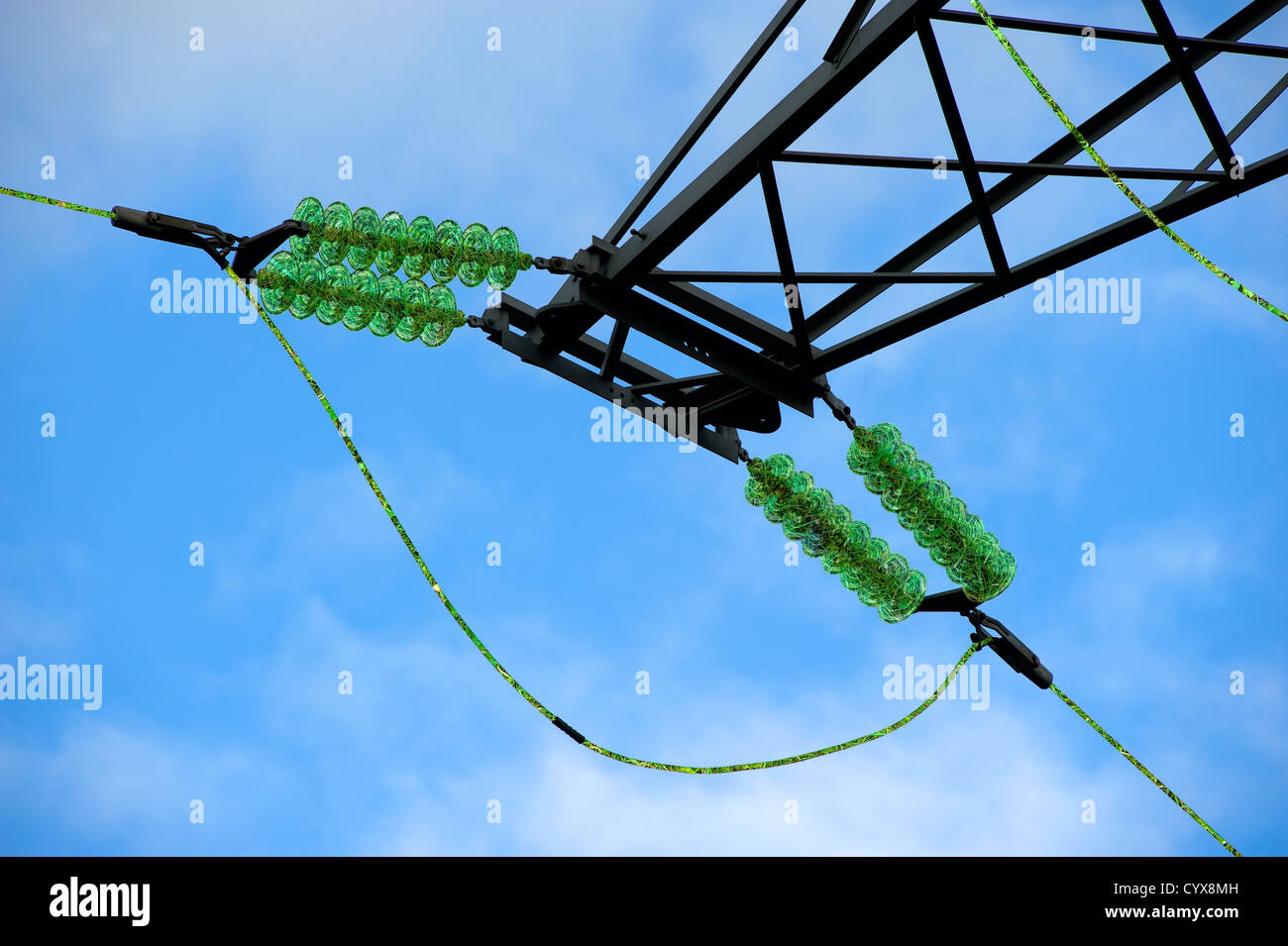 Green energy floating through power cables on an electricity pylon. Stock Photo