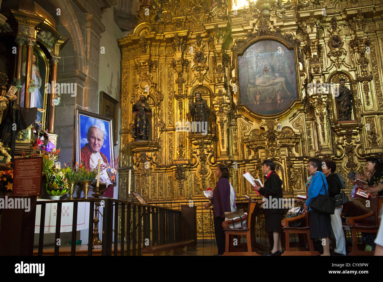 Women praying to/ for Pope John Paul II at a side chapel in Metropolitan Cathedral of the Assumption of Mary of Mexico City DF Stock Photo