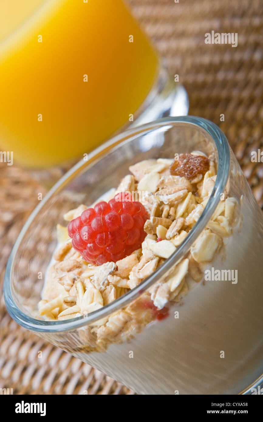 Fresh yogurt and muesli with a raspberry and a glass of orange juice