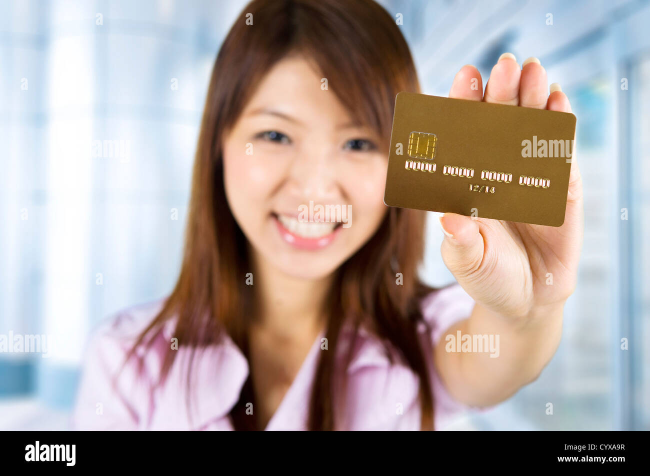 Asian woman holding a credit card, focus on the card. Card number and expiry date created by my own. Stock Photo