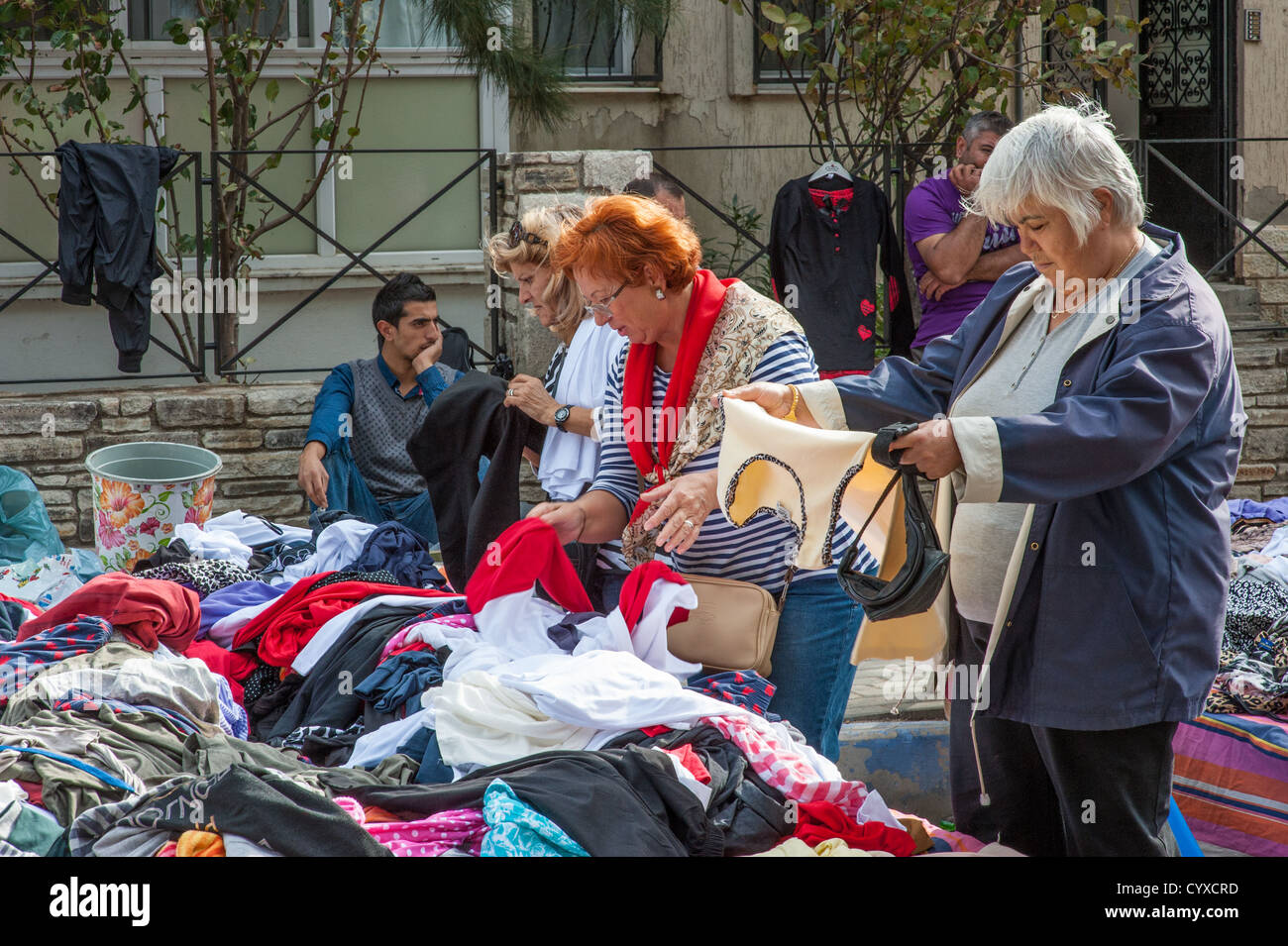 Women examine items of clothing at a market stall in Foca, Turkey. Stock Photo