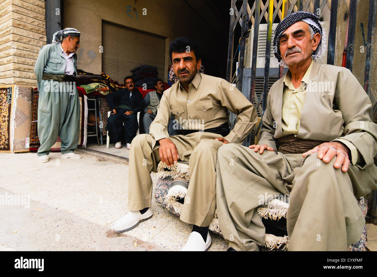 Kurdish men in traditional clothing sitting at a carpet shop in Qaysari Bazaar, Erbil, Kurdistan Region, Iraq Stock Photo