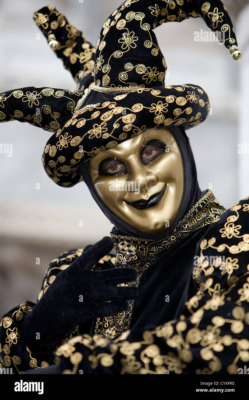 A joker at the Venice carnival in St. Marc's Square in a gold and black costume Stock Photo