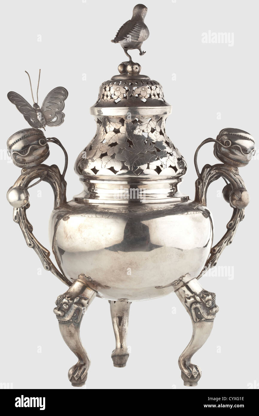 A silver scenter,China or Vietnam,circa 1900 Round body standing on three curved legs with dragon's heads.On either side a handle formed like a branch decorated with three-dimensional fruits and a moveable butterfly sitting on one handle.Opposite butterfly missing.The neck with openwork leaf decoration,the cap with floral decoration and an affixed three-dimensional bird.On the obverse side the talismanic Chinese inscription 'it may last 2000 years...' In the bottom Chinese punchmarks.Height 36.5 cm,weight 787 g.Allegedly a personal present by the Viet,Additional-Rights-Clearences-Not Available Stock Photo