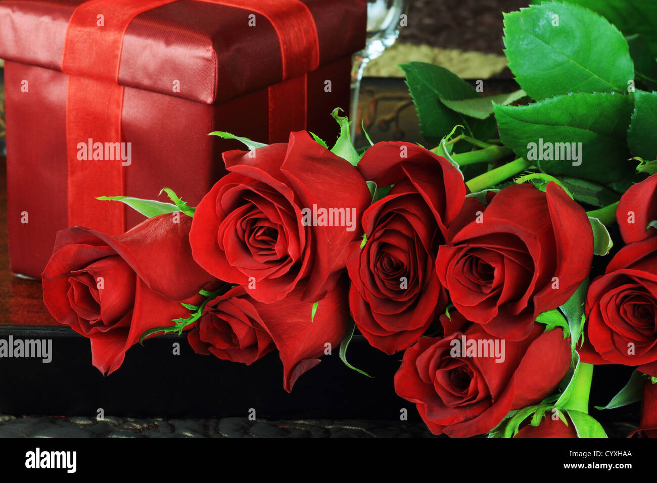 Upclose image of beautiful long stem red roses with gift in a breakfast tray on a bed. Stock Photo