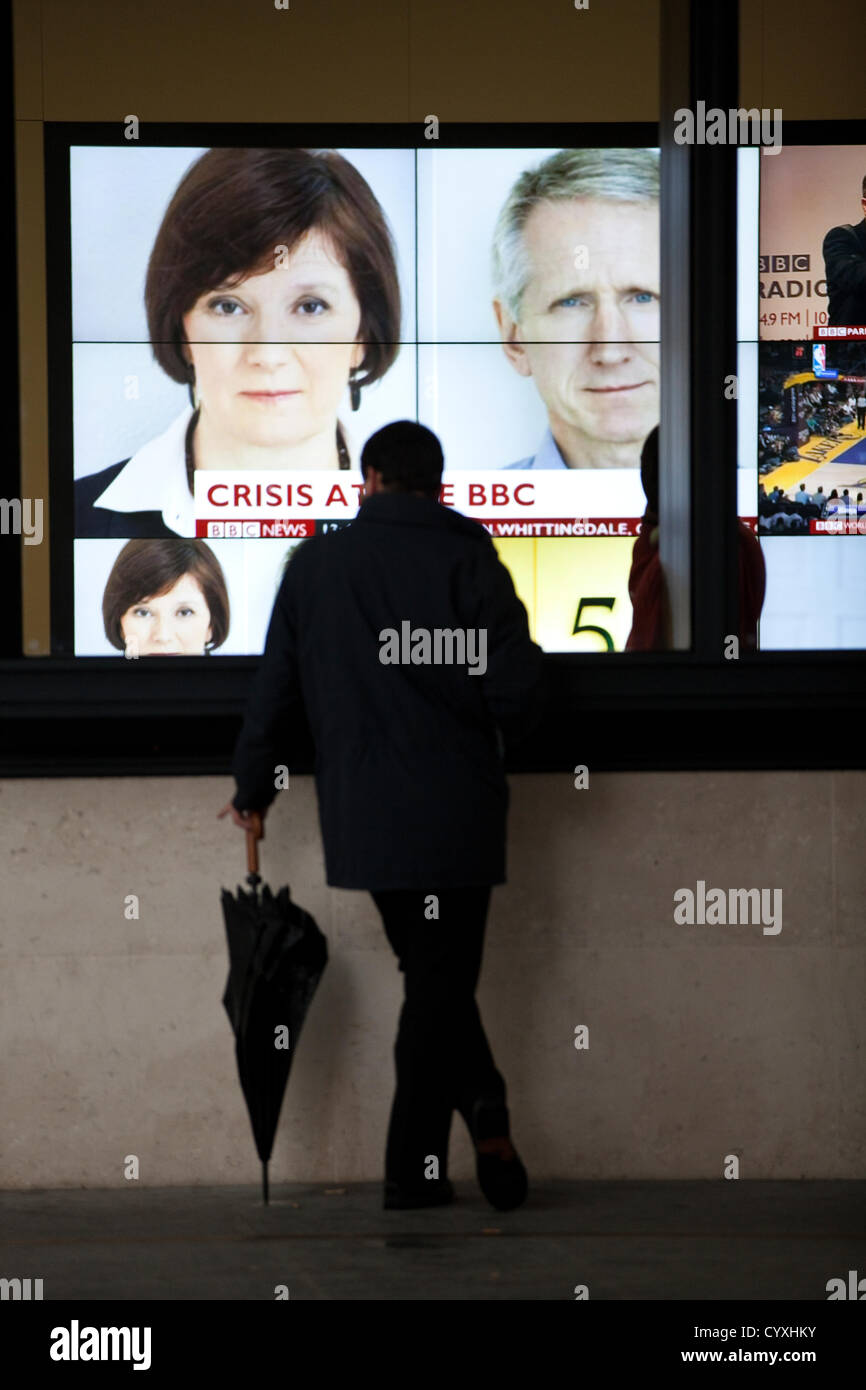 BBC Portland Place, London, UK. 12.11.2012 A man stops to watch the news headlines outside  the BBC News Corporations Broadcasting House in Portland Place as BBC announces the head of news Helen Boaden and her deputy Steve Mitchell have both resigned today. Stock Photo