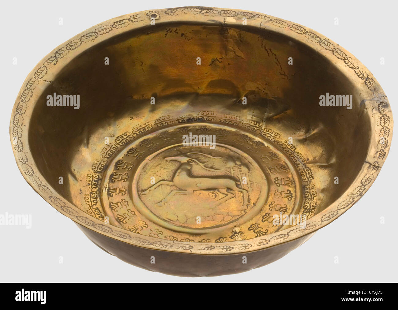 A cast brass basin(Beckenschlägerschüssel)with hunting decoration,Nuremberg,around 1500 A small deep brass basin surrounded with a narrow flanged rim.In the bottom center there is a running stag in relief in front of trees and flowering vines,surrounded by two embossed decorative friezes.The rim is embossed with decorative oak leaves.One old suspension hole,and several small repairs.Diameter 27 cm.The stag is one of the very rare motifs used on a Beckenschlägerschüssel.It is subject to both hunting and Christian interpretation,historic,historical,,Additional-Rights-Clearences-Not Available Stock Photo