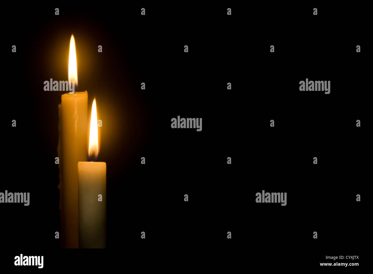two lit candles against a dark background Stock Photo Alamy