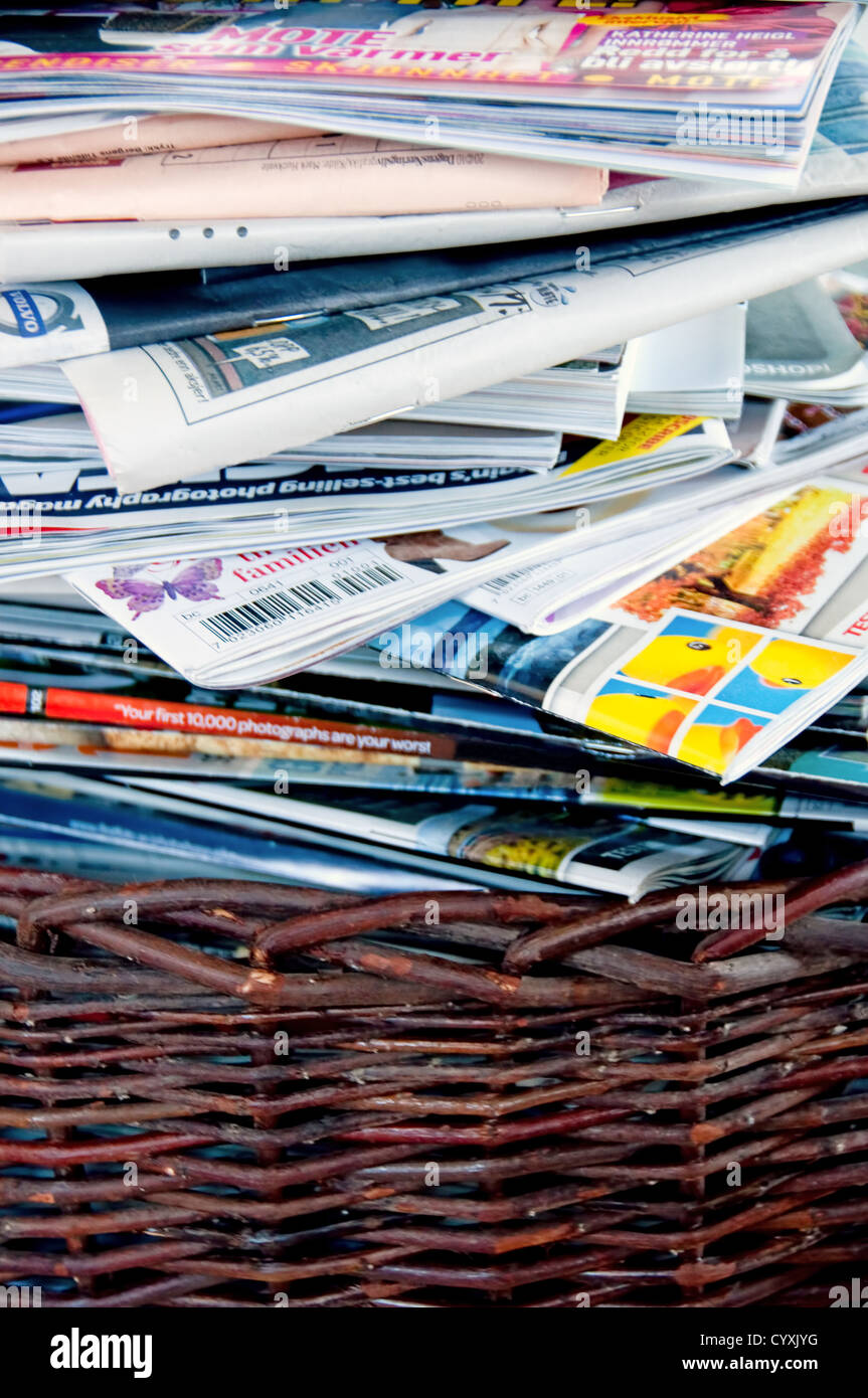 A stack of magazines and newspaper in a brown basket Stock Photo