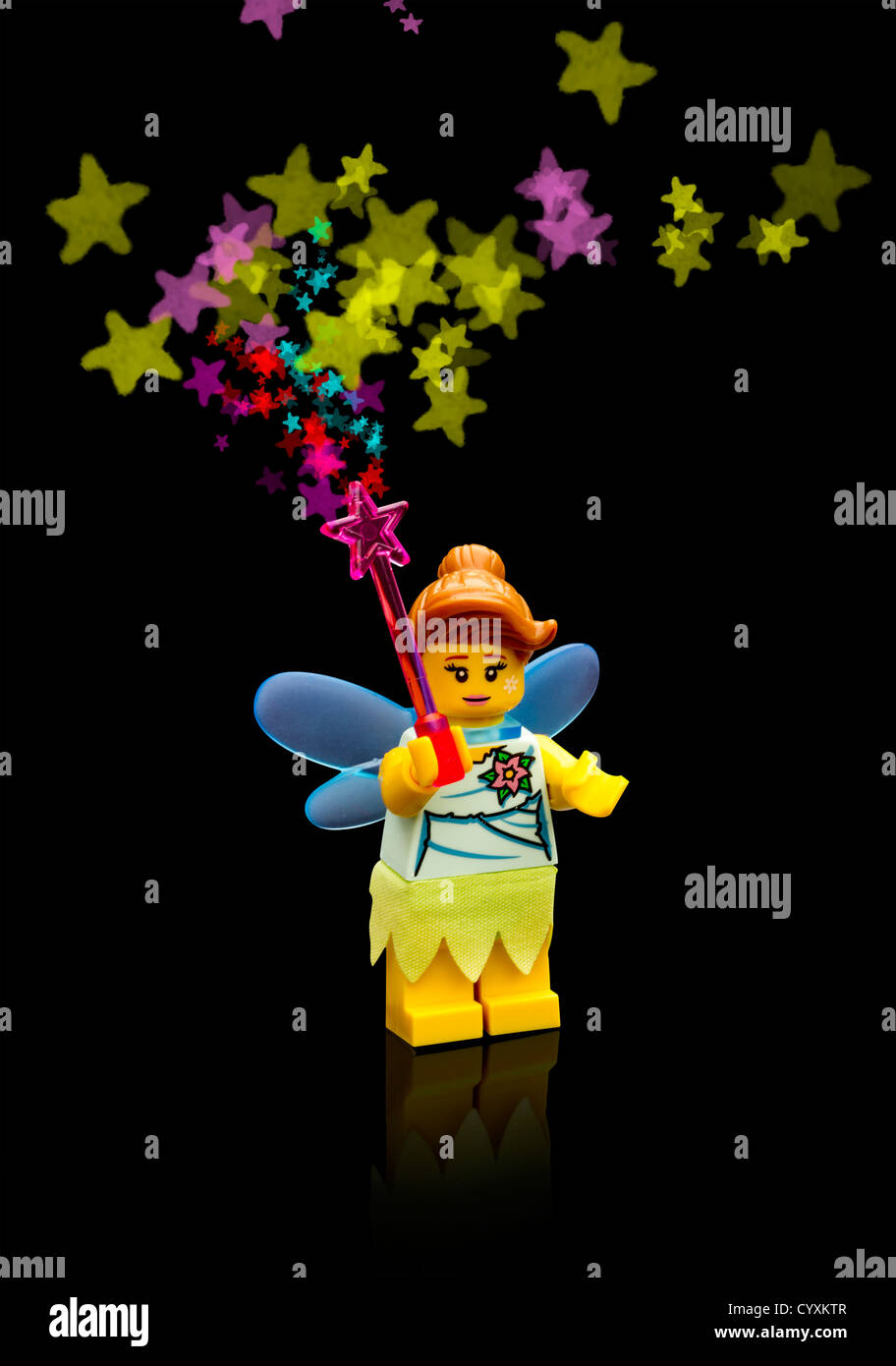 Lego fairy waving her wand creating colourful stars in front of a black background Stock Photo