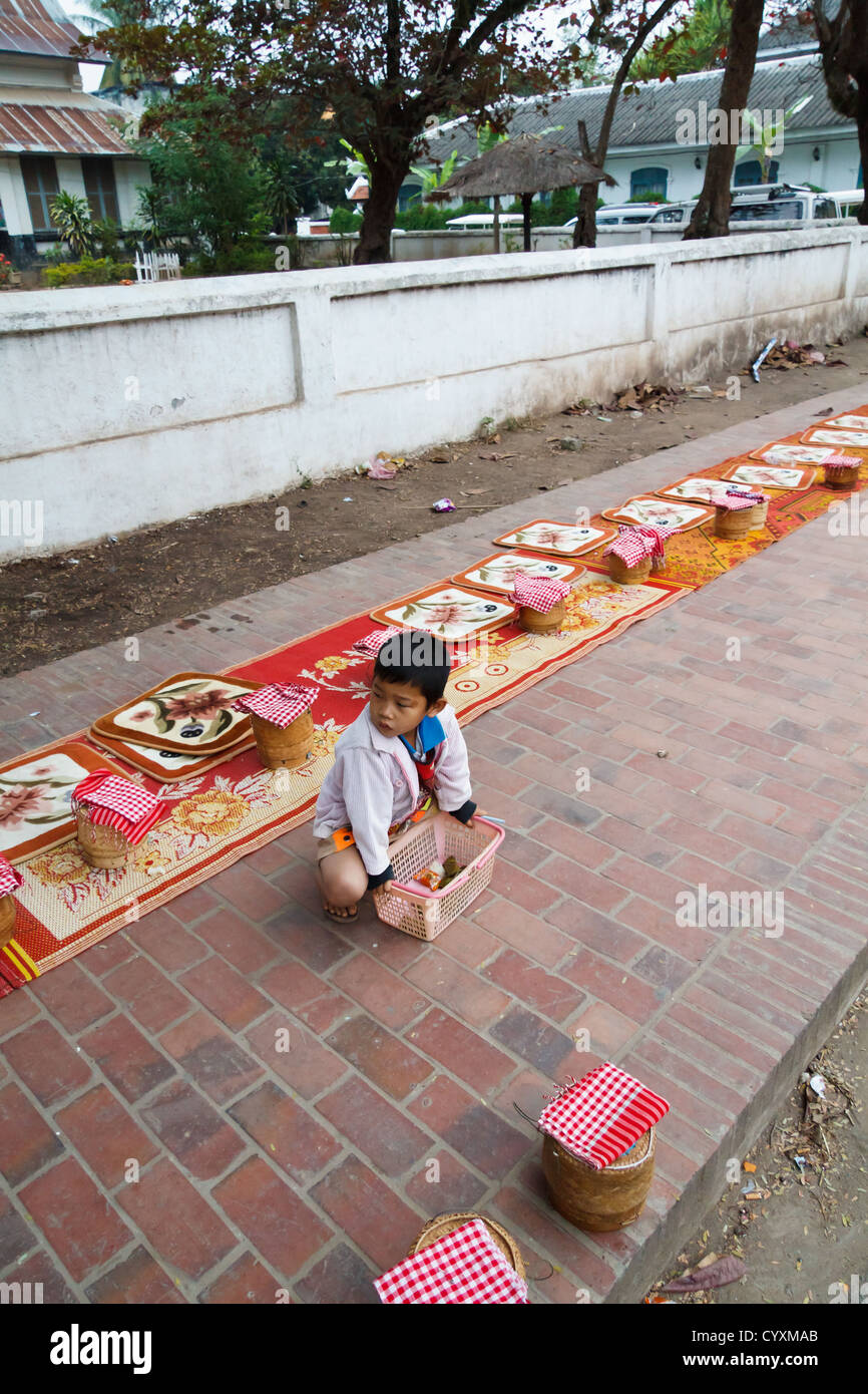 Little Boy on the Sidewalk in Luang Prabang after Alms Giving to the Monks, Laos Stock Photo