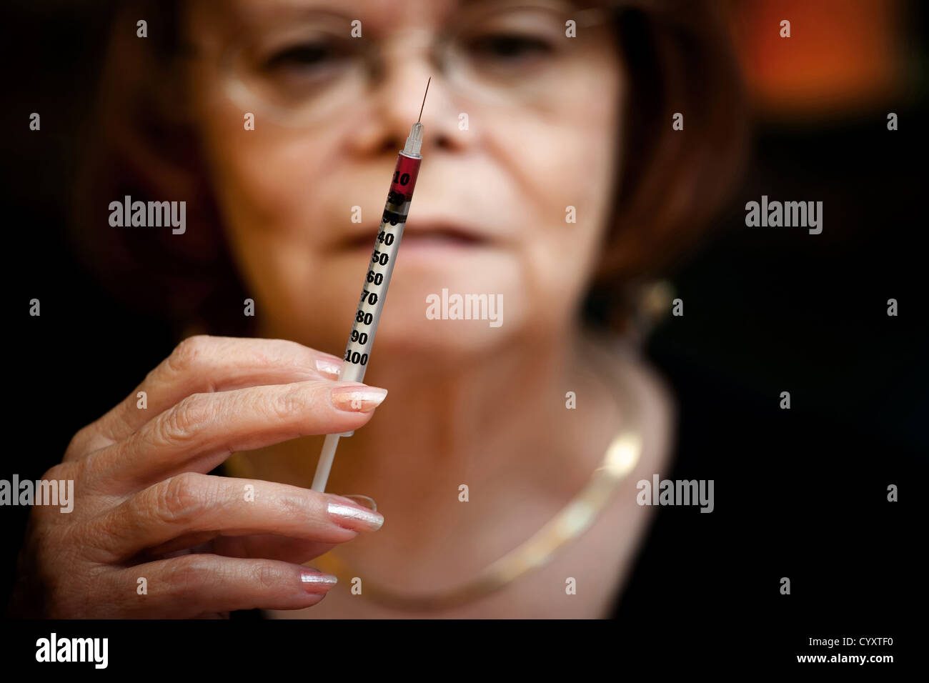 Senior woman looking at small hypodermic needle Stock Photo