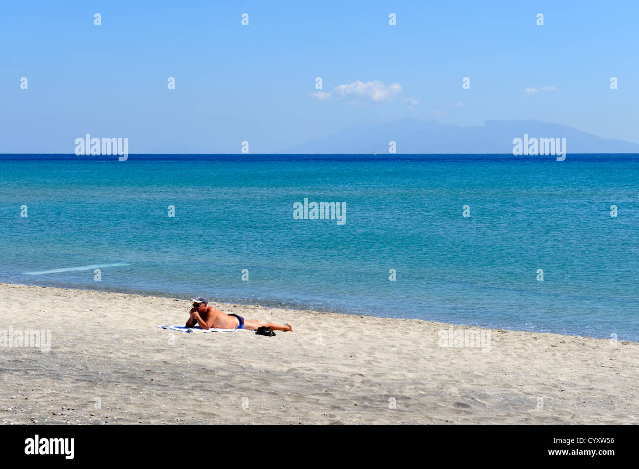 One person on sandy beach with blue Aegean sea Kardamena, island of Kos, Greece Stock Photo
