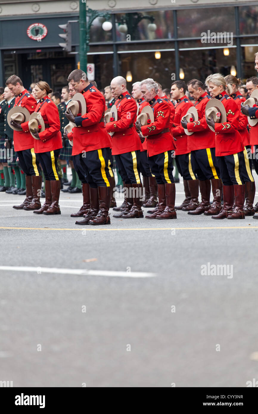 Mounties hold their hats and bow their heads on Remembrance Day at the Cenotaph in Vancouver's Victory Square. Stock Photo