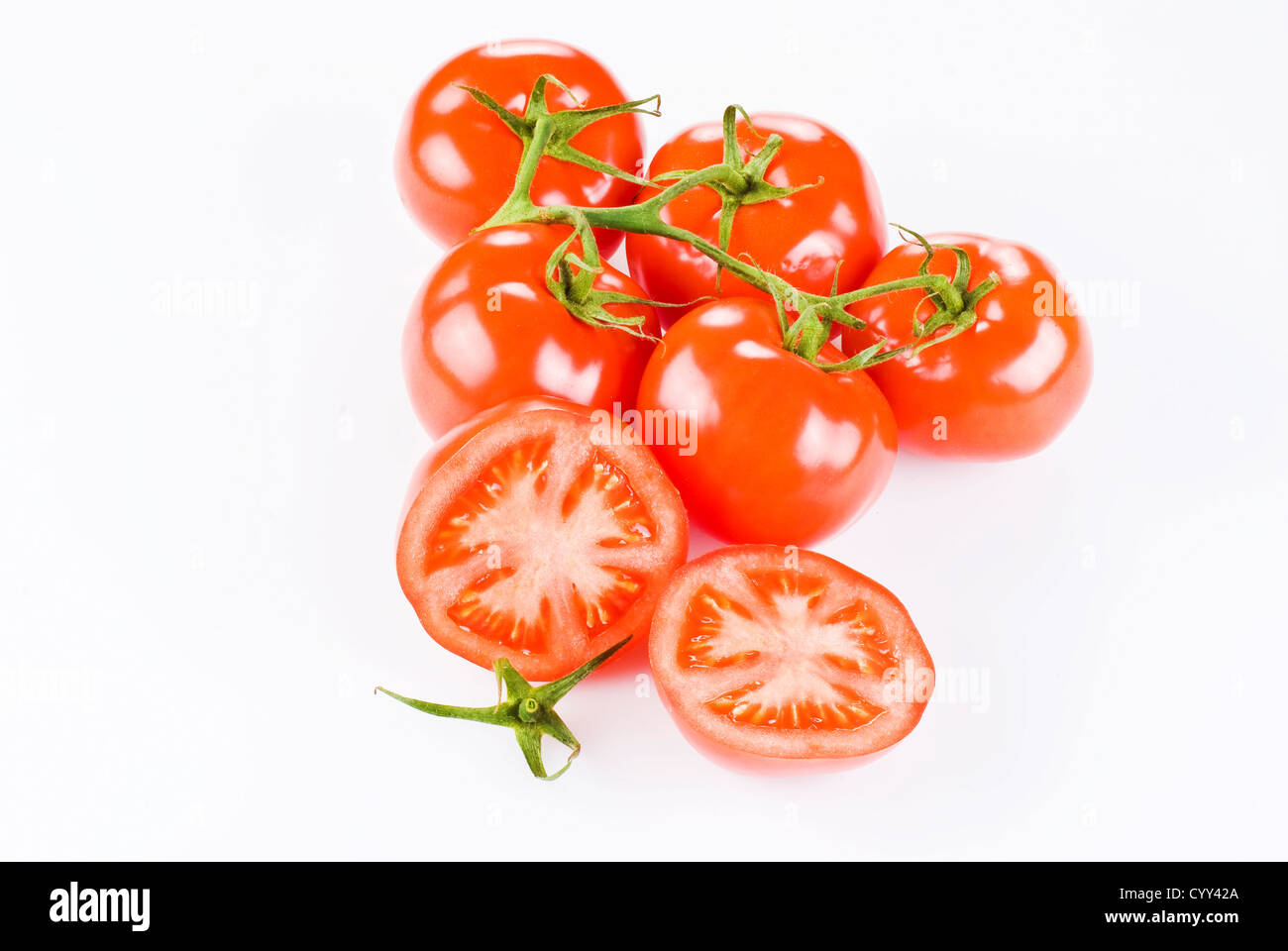 Bunch of tomatoes with two halves over white background Stock Photo